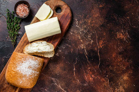 Butter spread and foodstuff toasts on a wooden cutting board. Dark background. Top view. Copy spaceの写真素材
