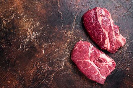 Raw Chuck eye roll beef steak on butcher table. Dark background. Top view. Copy spaceの写真素材