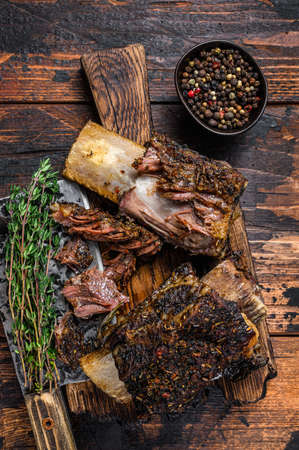 BBQ short chuck beef ribs with herbs and meat cleaver. Dark wooden background. Top viewの写真素材