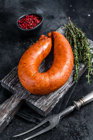 Bavarian Smoked sausage on a wooden rustic board with thyme. Black background. Top view