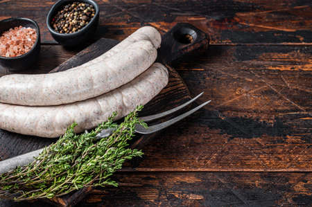 Munich traditional white sausages on a wooden board with thyme. Dark wooden background. Top view. Copy spaceの写真素材