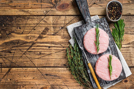 Raw burgers patty from organic chicken and turkey meat with thyme and rosemary. wooden background. Top view. Copy spaceの写真素材