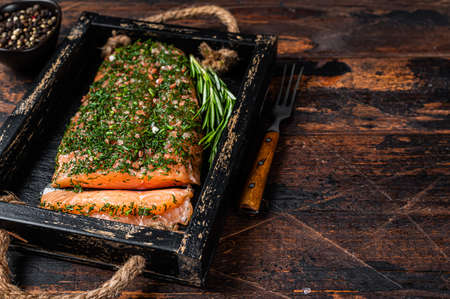 Salmon Gravlax cured with dill and salt in wooden tray. Dark wooden background. Top view. Copy spaceの写真素材