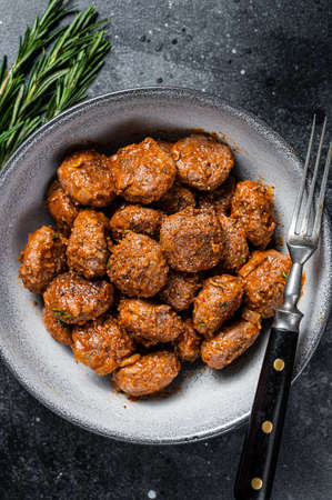Roasted Meatballs in tomato sauce from ground beef and pork meat with rosemary. Black background. Top viewの写真素材