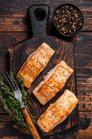Fried Salmon Fillet Steaks on a wooden board with thyme. Dark wooden background. Top viewの写真素材