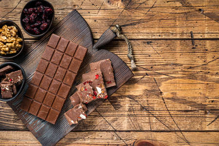 Dark chocolate bar with hazelnuts, peanuts, cranberries and freeze dried raspberries on a wooden...