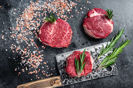 Fillet Mignon tenderloin raw meat beef steaks on butchery table. Black background. Top viewの写真素材