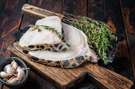 Fresh Raw wolf fish o wolf fish Steak on a butcher board. Dark wooden background. Top view