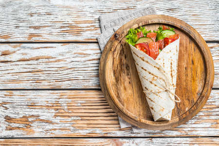 Wrap salmon sandwich, roll with fish and vegetables. White wooden background. Top view. Copy space