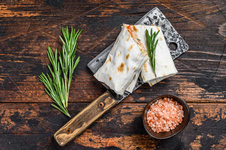Shawarma roll sandwich in a lavash with chicken, beef, mushrooms, cheese. Dark Wooden background....