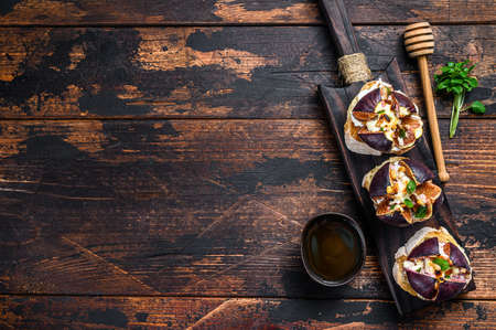 Bruschetta with camembert cheese and baked fig slices. Wooden background. Top view. Copy spaceの写真素材