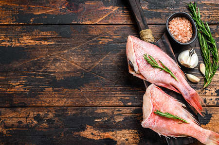 Whole raw fresh red perch or sea bass fish. Dark wooden background. Top view. Copy spaceの写真素材