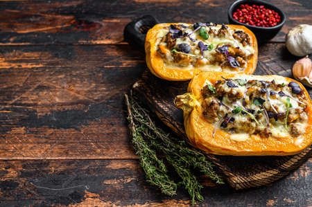 Baked pumpkin stuffed with ground meat, vegetables and herbs Dark wooden background. Top view. Copy spaceの写真素材