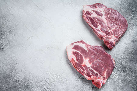 Raw pork neck meat steaks. White background. Top view. Copy spaceの写真素材