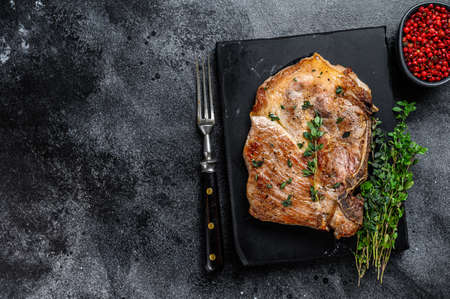 Grilled pork loin steak on a marble board. Black background. Top view. Copy space