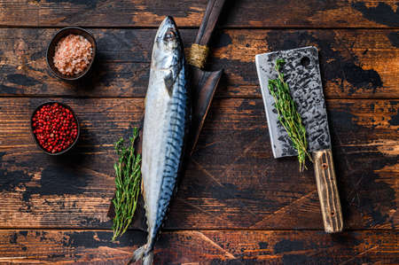 Fresh Raw fish Mackerel on a wooden cutting board with a cleaver. Dark wooden background. Top viewの写真素材