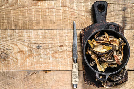 Mix of chopped wild dried mushrooms in a pan. wooden background. Top view. Copy spaceの写真素材