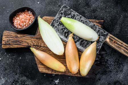 Fresh Raw cut baby shallot onion bulb on a wooden board. Black background. Top view