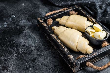 Raw fresh croissant in a wooden tray. Black background. Top view. Copy spaceの写真素材