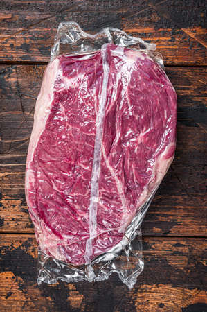 Raw dry aged beef round steak piece. Dark wooden background. Top viewの写真素材