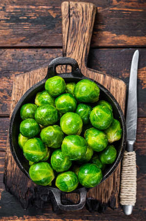 Boiled Brussels green sprouts cabbage in a pan. Dark wooden background. Top viewの写真素材