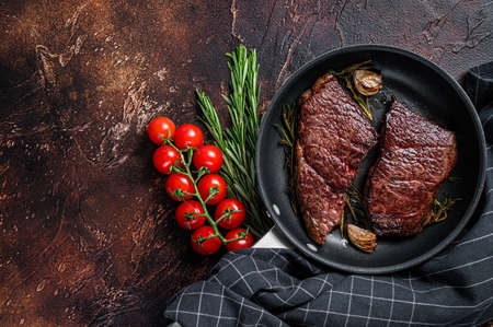Grilled denver beef meat steak in a pan with rosemary. Dark background. Top view. Copy spaceの写真素材