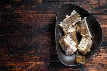 Roasted hake white fish in a plate. Dark wooden background. Top view. Copy spaceの写真素材