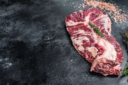 Hanger or onglet raw beef meat steak on butcher table with herbs. Black background. Top View. Copy spaceの写真素材