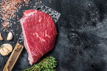 Fresh Raw rump beef cut or top sirloin cap steak on butcher cleaver. Black background. Top view. Copy spaceの写真素材