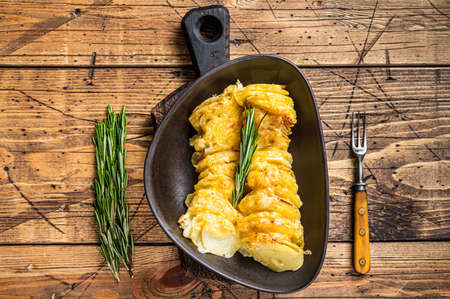 Potato casserole Gratin in a plate with herbs. wooden background. Top Viewの写真素材