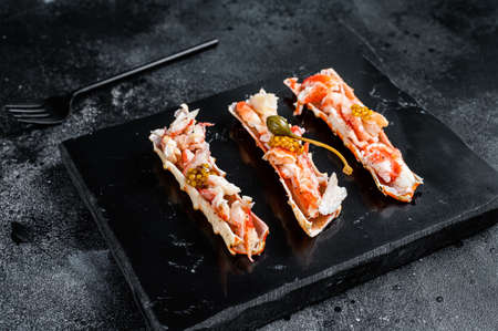 Crab leg meat in a sheel with herbs. Black background. Top view