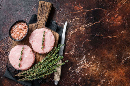 Fresh Raw burgers patty cutlet from chicken and turkey meat with herbs. Dark background. Top view. Copy spaceの写真素材