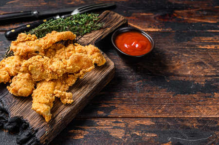 Chicken strips on a wooden cutting Board. Dark Wooden background. Top view. Copy spaceの写真素材