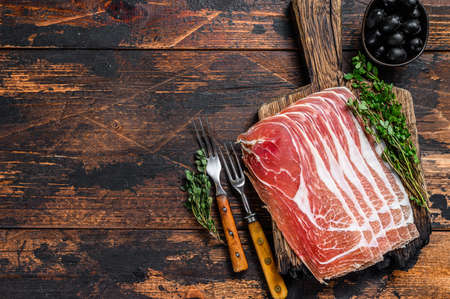 Traditional Spanish sliced Jamon Serrano ham on a cutting board. Dark wooden background. Top view. Copy spaceの写真素材
