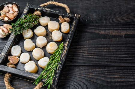 Fresh scallops meat in a wooden tray. Black wooden background. Top view. Copy spaceの写真素材