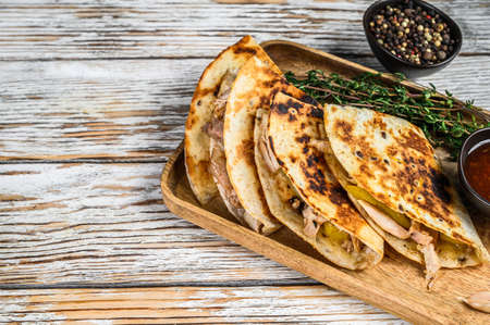 Vegetarian snacks quesadilla with vegetables and cheese on wooden tray. White wooden background. Top...
