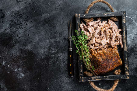 Bbq slow roast puilled pork meat in a wooden tray. Black background. Top view. Copy spaceの写真素材