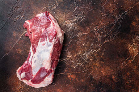 Raw lamb mutton shoulder meat on the bone. Dark background. Top view. Copy spaceの写真素材