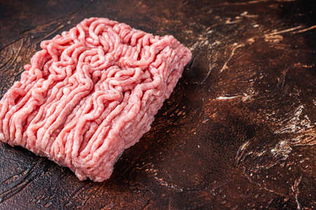 Raw ground chicken or turkey meat on brown table. Dark background. Top View. Copy spaceの写真素材
