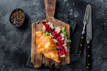 Croissant sandwich with Duck breast steak slices, arugula and sauce. Black background. Top Viewの写真素材