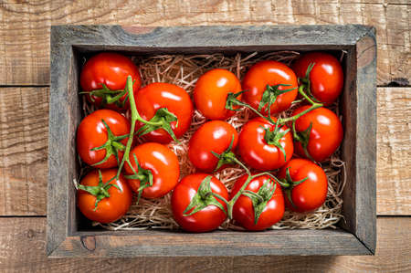 Red tomatoes in wooden market box. Wooden background. Top viewの写真素材