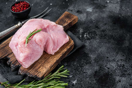 Fresh Raw whole big turkey breast fillet on wooden board. Black background. Top View. Copy spaceの写真素材