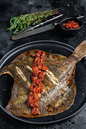 Roasted Flatfish or Flounder in a tomato sauce. Black background. Top viewの写真素材