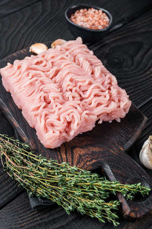 Fresh Raw mince or ground chicken meat on wooden chopping board with thyme. Black wooden background. Top viewの写真素材