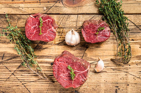 Raw Fillet mignon steaks, beef tenderloin on a wooden butcher table with meat fork. wooden background. Top viewの写真素材