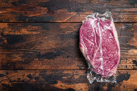 Raw dry aged beef round steak piece. Dark wooden background. Top view. Copy spaceの写真素材