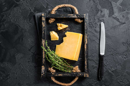 Swiss Hard cheese piece in wooden tray. Black background. Top viewの写真素材