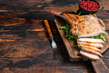 Grilled and sliced tomahawk pork chop meat steak on a marble board. Dark Wooden background. Top view. Copy spaceの写真素材