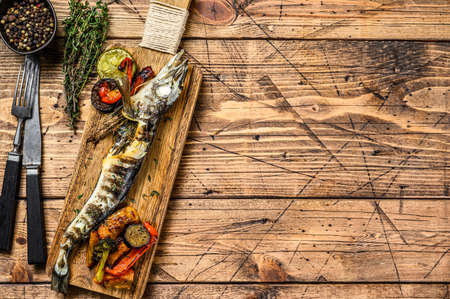Grilled whole icefish with vegetables. Wooden background. Top view. Copy spaceの写真素材