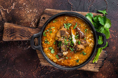 Kharcho soup with lamb meat, rice, tomatoes, carrots, peppers, walnuts and spices. Dark background. Top viewの写真素材